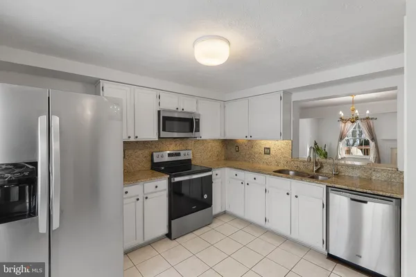 a kitchen with white cabinets sink and stainless steel appliances