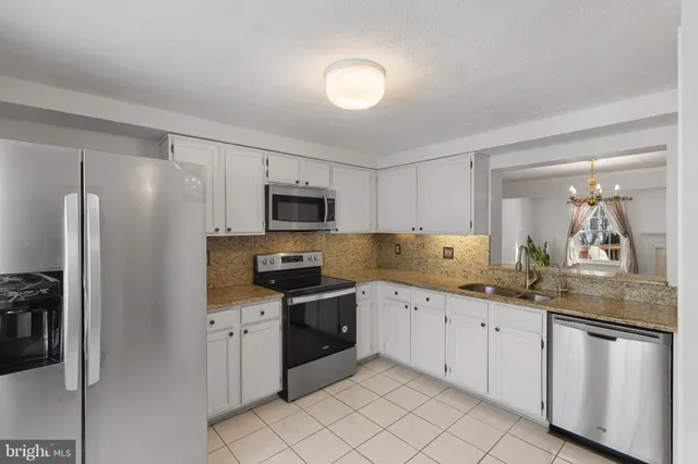 a kitchen with white cabinets sink and stainless steel appliances