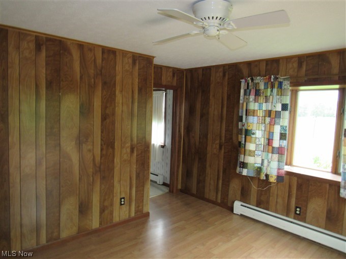 2189 Sentinel Road Dorset, OH 44032 - Photo 8 of 28 Wood floored spare room with a baseboard heating unit, wooden walls, and ceiling fan