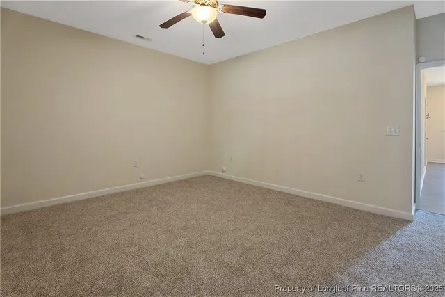 en empty room with ceiling fan and window