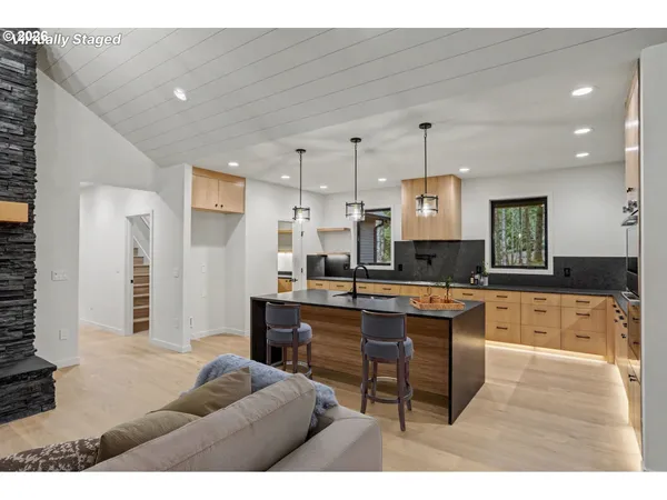 a open kitchen with stainless steel appliances kitchen island granite countertop a refrigerator a stove a sink dishwasher and white cabinets with wooden floor