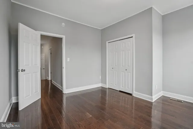 an empty room with wooden floor & closet area