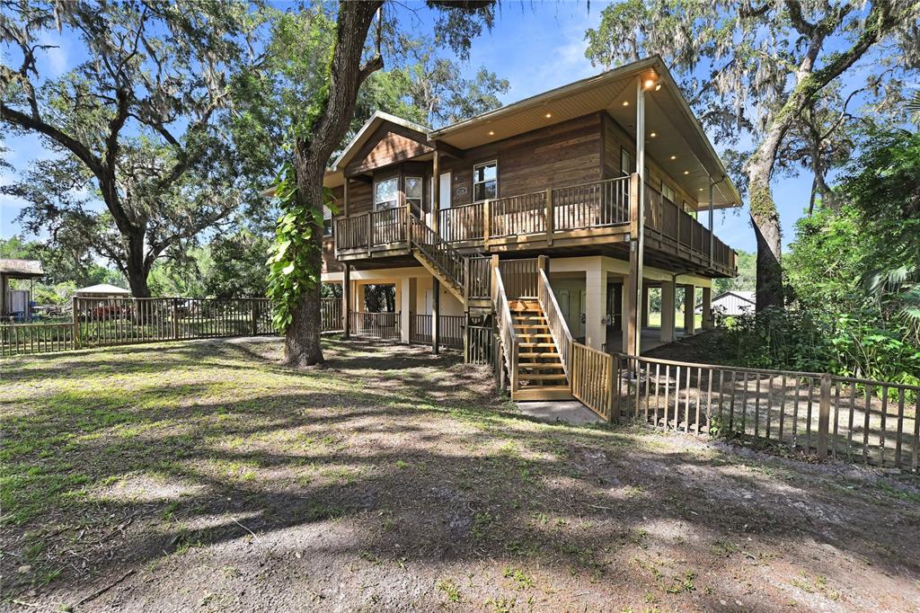 a view of a house with a big yard and large tree