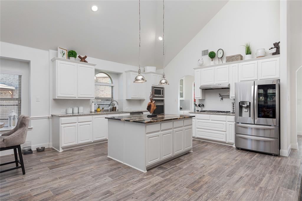 1008 Hummingbird Court Forney, TX 75126 - Photo 5 of 34 a kitchen with granite countertop a white stove top oven and cabinets