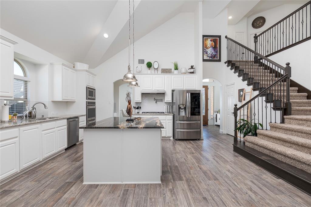 1008 Hummingbird Court Forney, TX 75126 - Photo 6 of 34 a kitchen with stainless steel appliances kitchen island wooden floors and white cabinets