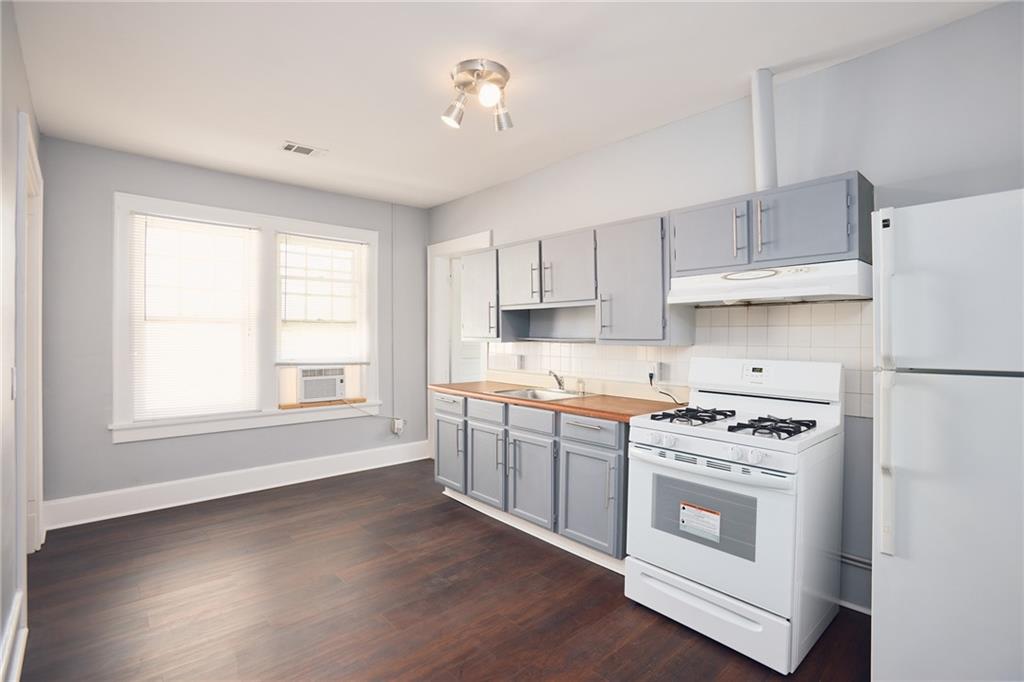 887 Myrtle Street Northeast, Unit 5 Atlanta, GA 30309 - Photo 3 of 11 a kitchen with cabinets appliances wooden floor and a window