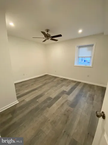 an empty room with a ceiling fan and wooden floor