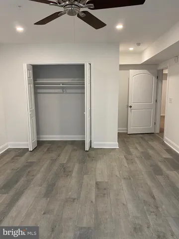 a view of a hallway to a room with wooden floor and cabinet