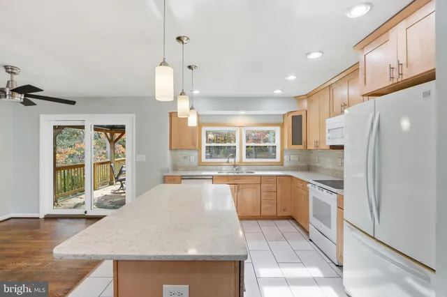 a kitchen with stainless steel appliances granite countertop a refrigerator a sink a stove and white cabinets with wooden floor