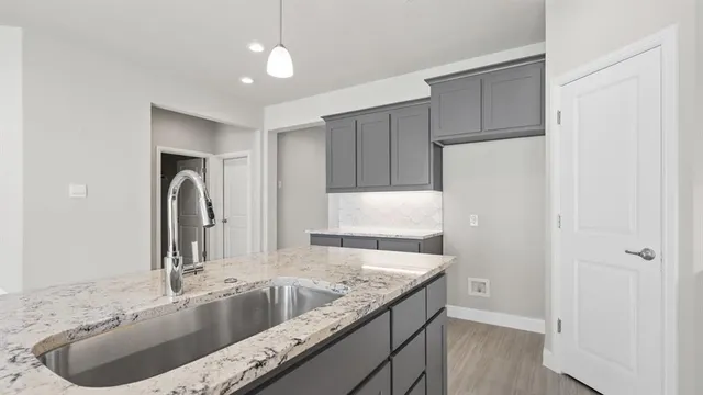 a kitchen with stainless steel appliances granite countertop a refrigerator a sink dishwasher a stove and white cabinets with wooden floor