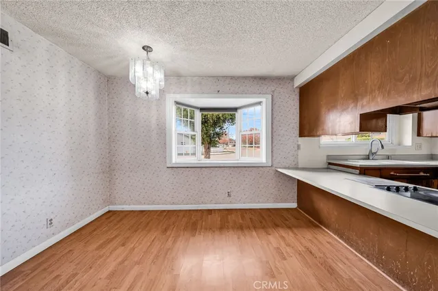 a kitchen with stainless steel appliances granite countertop a sink dishwasher and a refrigerator with wooden floor