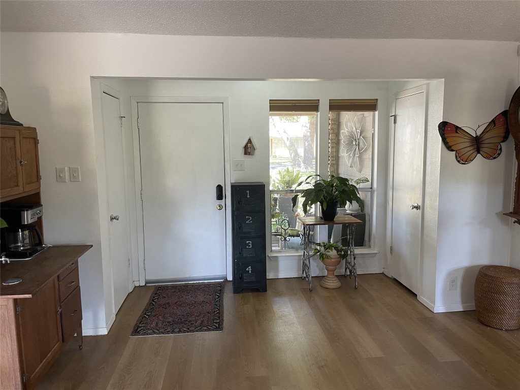 9206 Robins Nest Lane Austin, TX 78729 - Photo 4 of 18 a view of a hallway with wooden floor and a living room