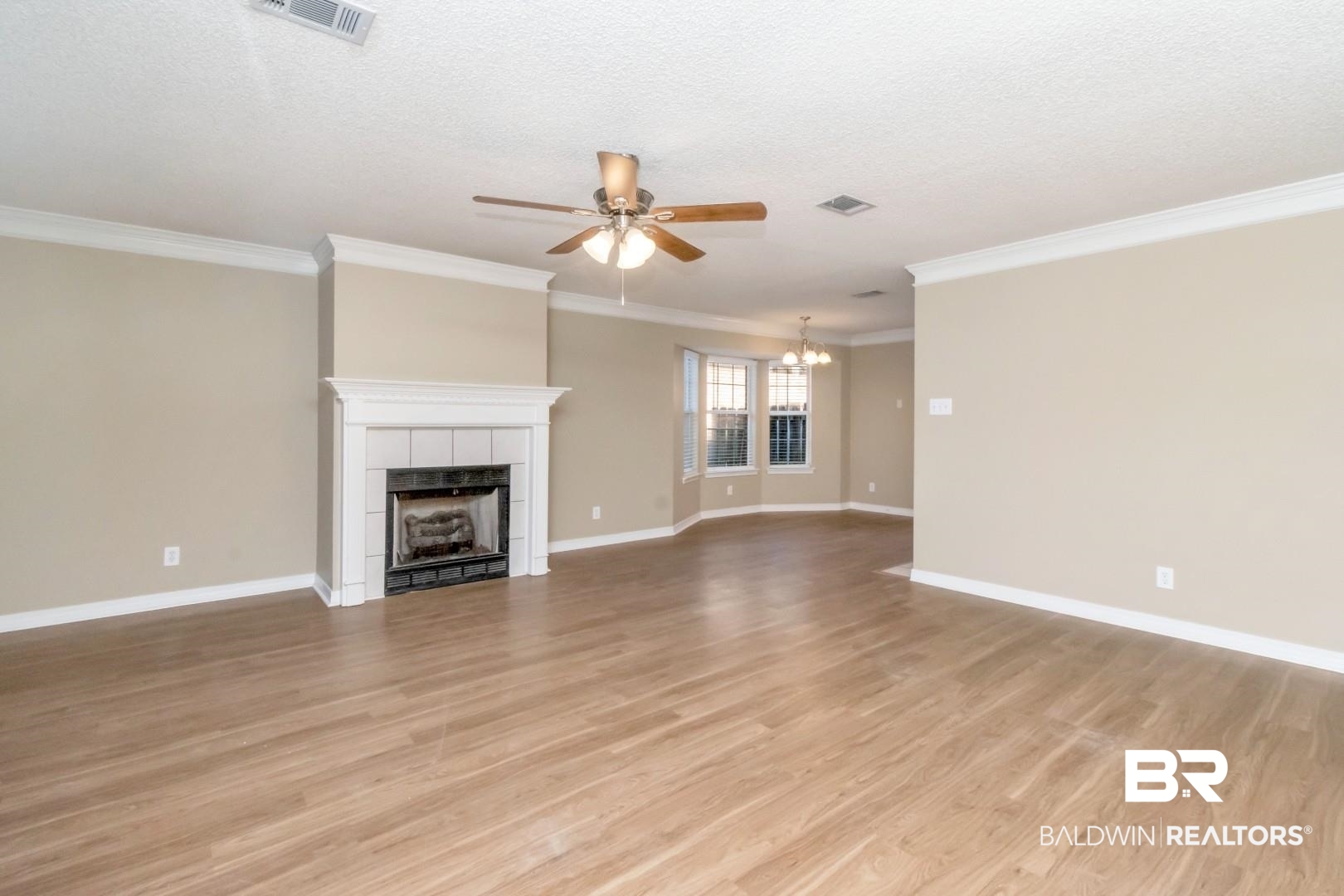 6482 Cedar Bend Court Mobile, AL 36608 - Photo 3 of 26 Unfurnished living room featuring a tiled fireplace, light wood-style flooring, a ceiling fan, a textured ceiling, and ornamental molding