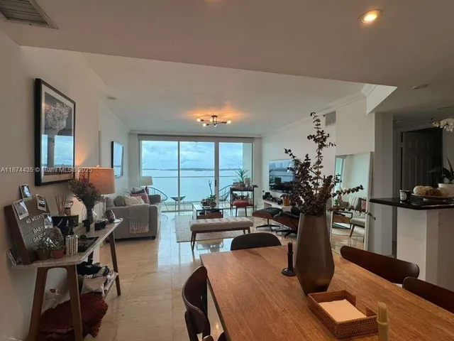 a living room with furniture a potted plant and a large window