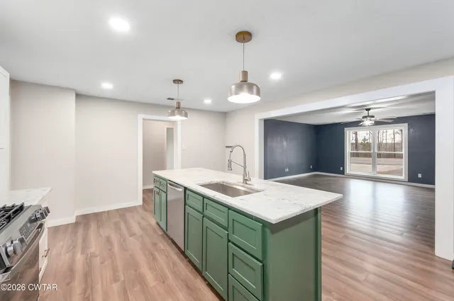 a kitchen with a sink chandelier and wooden floor