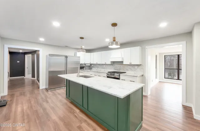 a kitchen with a sink a stove cabinets and wooden floor