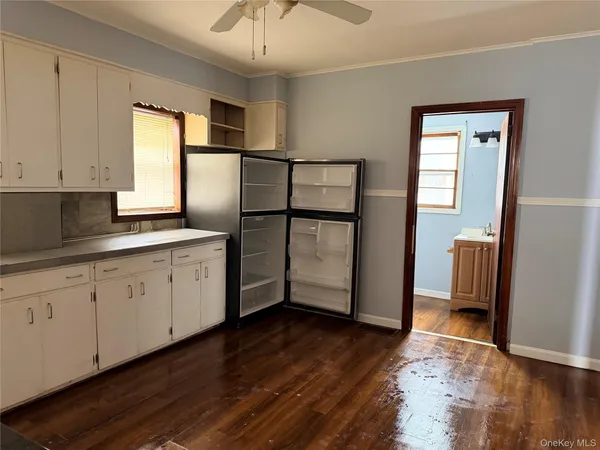 a kitchen with stainless steel appliances granite countertop a refrigerator a sink and white cabinets with wooden floor