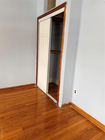 a view of an empty room with wooden floor and closet