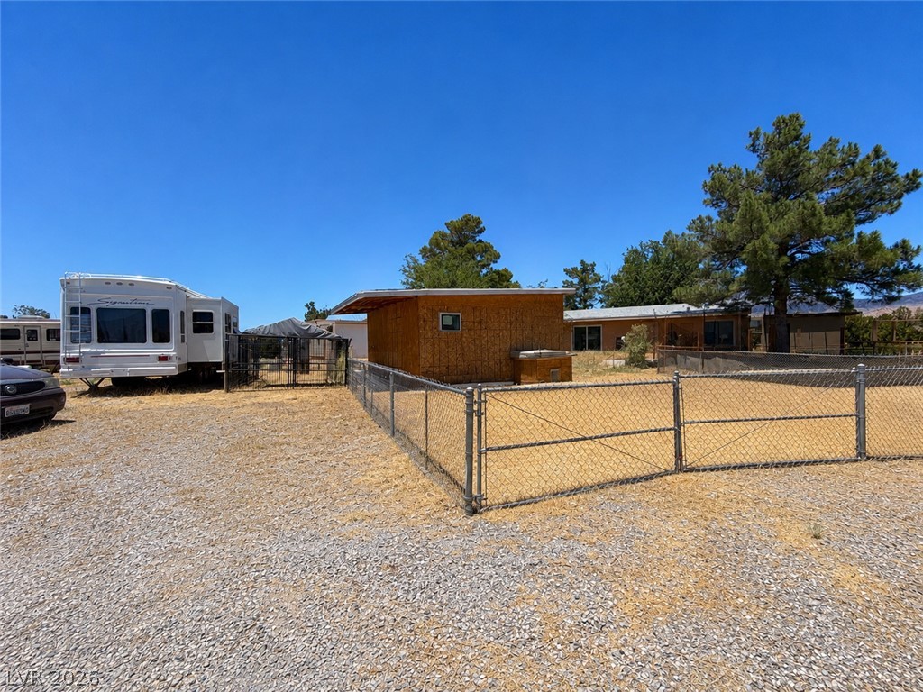 1611 West Blosser Ranch Road Pahrump, NV 89060 - Photo 22 of 25 A spacious gravel parking area and fenced yard create a versatile outdoor space with mountain views.