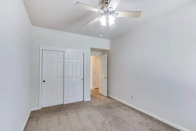 an empty room with closet and a chandelier fan