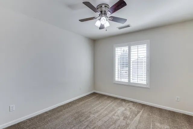 an empty room with a window and a fan