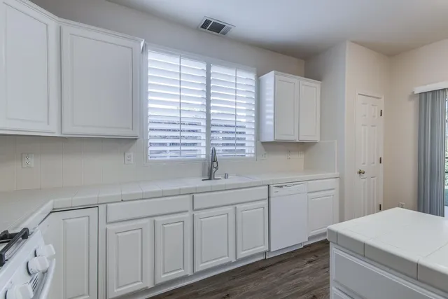a kitchen with white cabinets and sink
