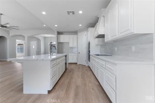 a large white kitchen with a large counter top and stainless steel appliances