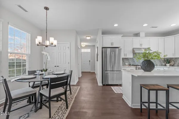a dining room filled chandelier and kitchen view