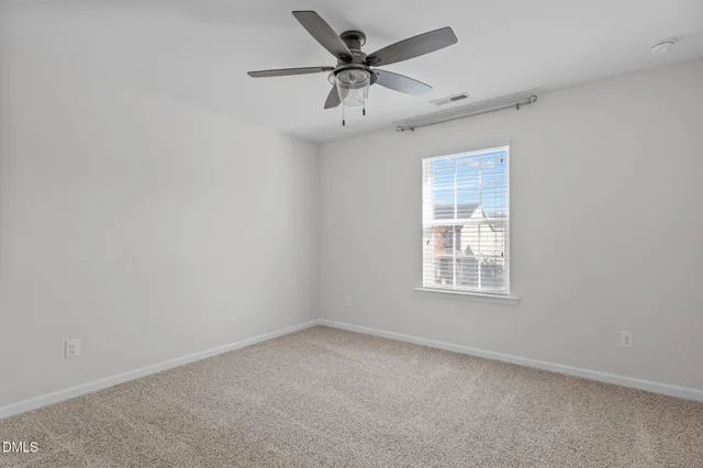an empty room with a window and a ceiling fan