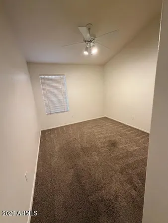 an empty room with a chandelier fan and windows