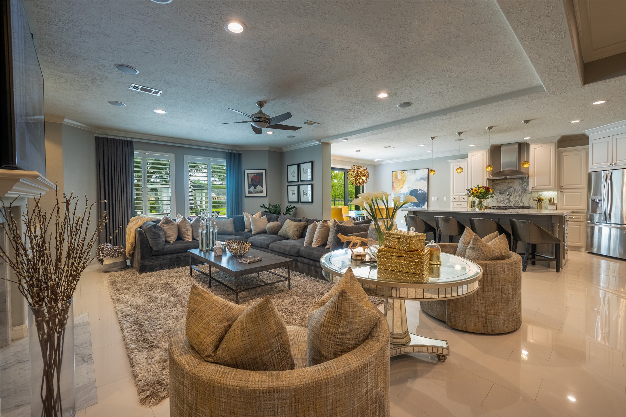 4002 Silver Ridge Boulevard Missouri City, TX 77459 - Photo 13 of 50 This is a spacious, open-concept living room that flows seamlessly into a modern kitchen with top-of-the-line appliances and a cozy dining area. The room features plush seating, elegant decor, and ample natural light from large windows with plantation shutters.