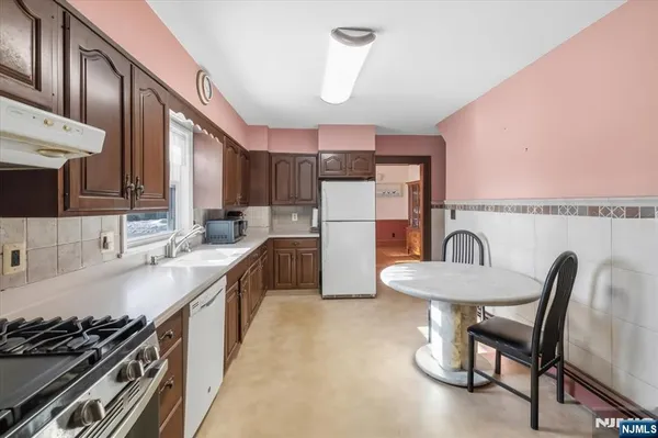 a kitchen with stainless steel appliances granite countertop a sink a stove a refrigerator cabinets and chairs