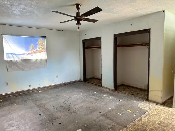 an empty room with windows and a ceiling fan