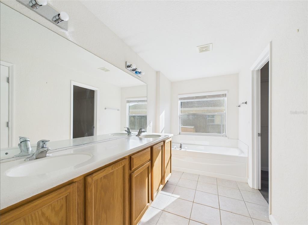 5208 Southwest 39th Street Ocala, FL 34474 - Photo 15 of 55 a spacious bathroom with a granite countertop sink a mirror and a bathtub