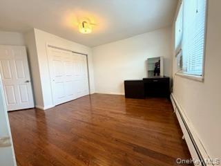216-11 73rd Avenue, Unit DUPLEX Queens, NY 11364 - Photo 5 of 27 Unfurnished bedroom with a baseboard radiator, dark wood-type flooring, and a closet