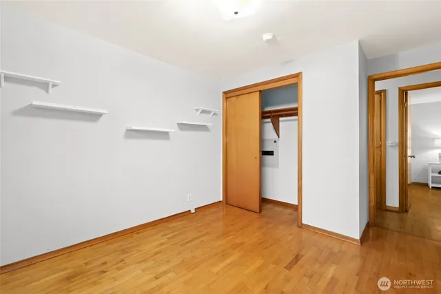 a view of an empty room with wooden floor and a bathroom