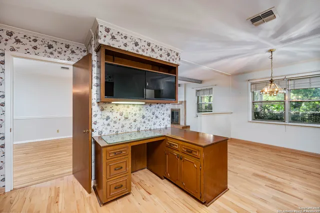 a living room with stainless steel appliances kitchen island granite countertop a stove and a wooden floors