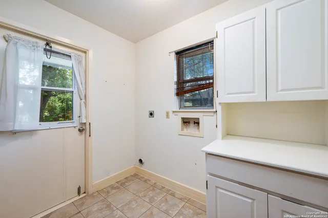 a view of a kitchen with white cabinets and a window