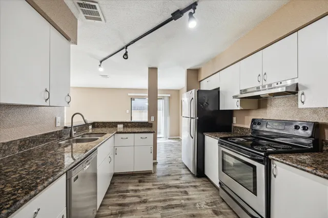a kitchen with granite countertop a sink stainless steel appliances and cabinets