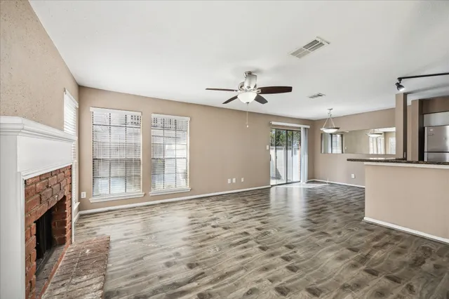 a view of an empty room with a fireplace and wooden floor