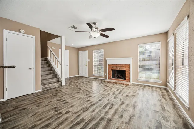 a view of a livingroom with wooden floor a ceiling fan and a window