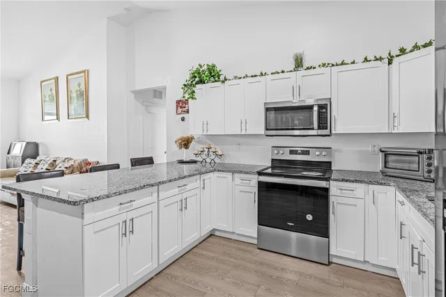 a kitchen with granite countertop white cabinets and white appliances