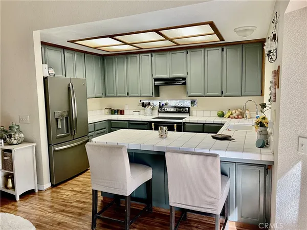 a kitchen with stainless steel appliances a table chairs refrigerator and sink
