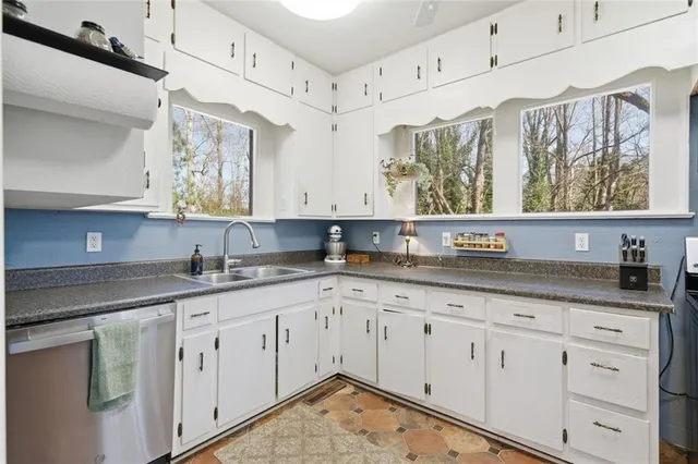 a kitchen with granite countertop white cabinets white stainless steel appliances and sink