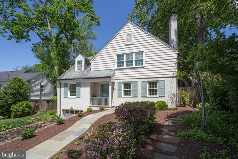 a view of a white house next to a yard with potted plants