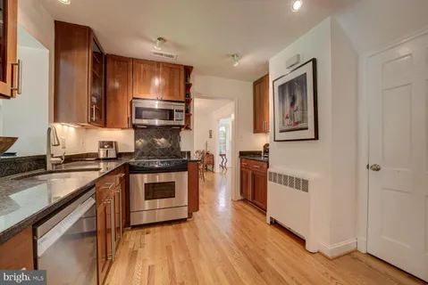 a kitchen with stainless steel appliances granite countertop a stove cabinets and wooden floor