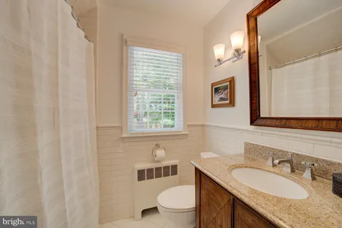 a bathroom with a granite countertop sink a toilet and a mirror