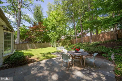 a backyard of a house with table and chairs plants