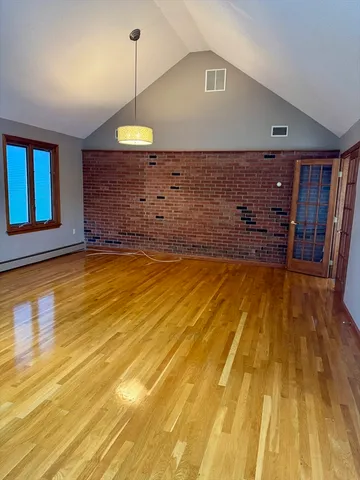 a spacious bedroom with a bed and wooden floor