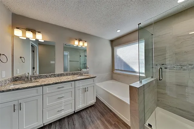 a bathroom with a granite countertop double vanity sink a mirror and a bathtub